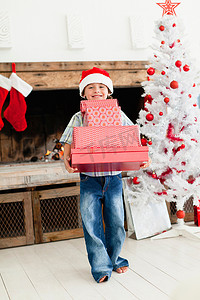 戴圣诞帽的男孩摄影照片_戴着圣诞帽的男孩带着圣诞礼物