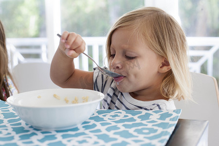 女孩用勺子从碗里吃早餐
