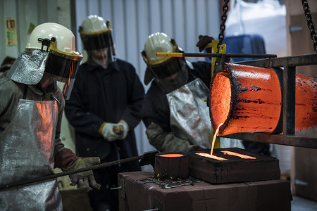 男性铸造工人在青铜铸造厂浇注青铜熔炉