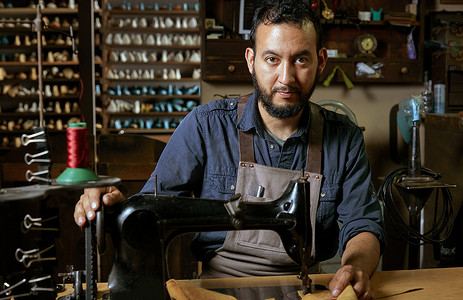 传统鞋店缝纫机前的男鞋匠画像