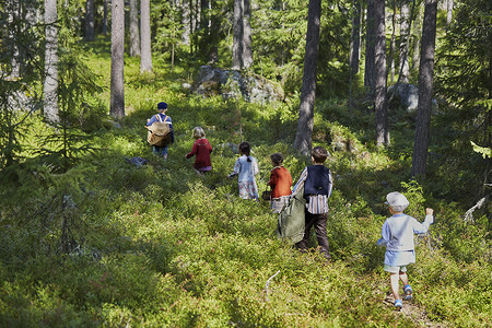 六个穿着复古服装的男孩和女孩走在森林里