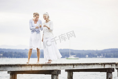 两个女性朋友沿着码头走着笑着