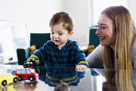 几桌子摄影照片_中年妇女和男婴在桌子上玩玩具车