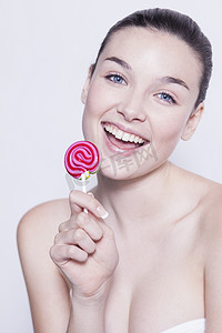 棒棒糖粉色背景摄影照片_美丽的年轻女子手持粉色棒棒糖的肖像