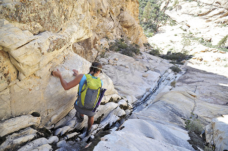 美国内华达州威尔逊山年轻女攀岩者从缝隙中爬下的背影
