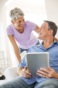 便携式摄影照片_成熟的夫妇一边使用数字平板电脑一边聊天