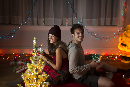 圣诞摄影照片_圣诞节一对年轻夫妇在客厅里交换礼物