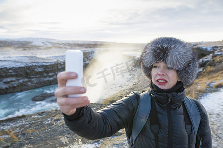 一名女子在位于冰岛西南部河峡谷的瀑布自拍
