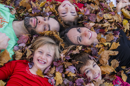 一家人头靠在一起躺在秋叶里