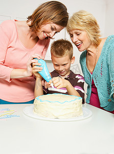 奶奶男孩和妈妈在装饰蛋糕