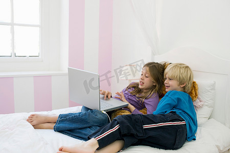躺在床上看笔记本电脑的男孩和女孩