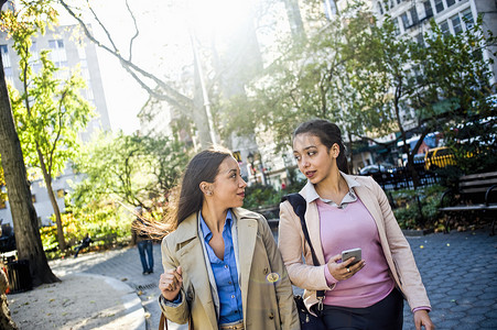 一对年轻的成年女性双胞胎在城市公园里聊天和散步