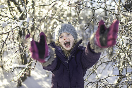 年轻的女孩笑着伸出双臂在雪地上