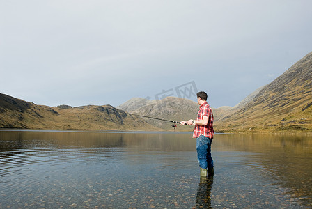 逃生竿摄影照片_一名男子在湖里钓鱼
