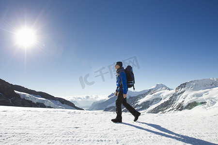 德力西墙壁开关摄影照片_一名男子在积雪覆盖的山上徒步旅行瑞士格林德尔瓦尔德的