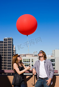大红色气球摄影照片_带着红色气球在屋顶上的朋友