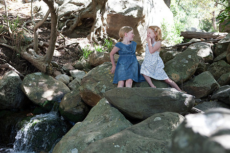 河边的少女摄影照片_两个女孩在河边的岩石上