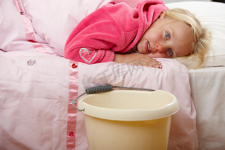 生病的女孩抱着水桶躺在床上