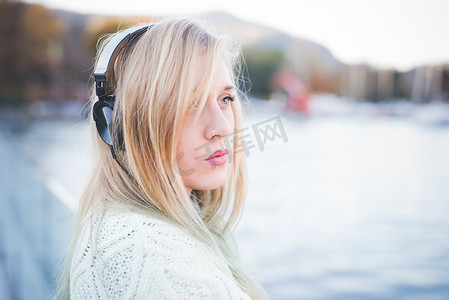 意大利科莫湖边的一名年轻女子一边听着耳机一边看着别处