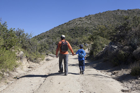 智利瓦尔帕莱索安第斯山区一对父子徒步走土路的后景