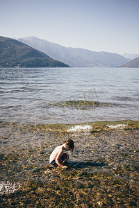 意大利伦巴第卢伊诺男孩蹲在浅水中俯瞰山脉的侧视