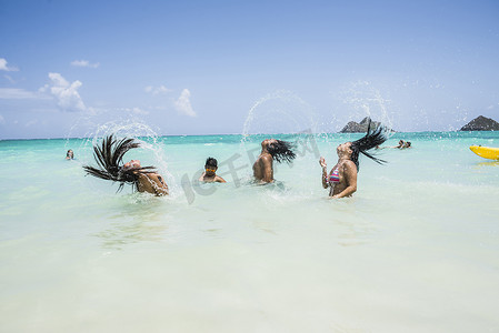 在美国夏威夷瓦胡岛拉尼凯海滩年轻女子将湿长的头发扔回大海的侧视