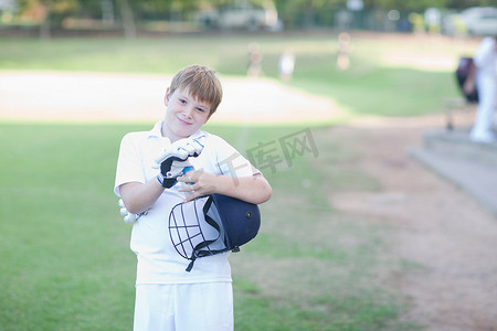 板球头盔摄影照片_戴着板球手套和头盔的男孩肖像