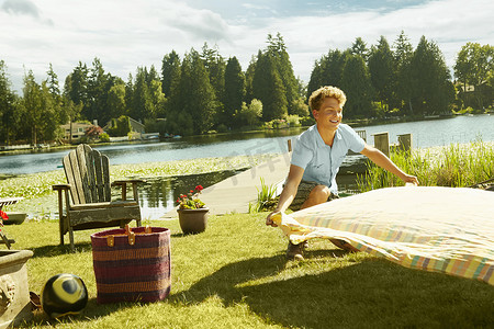 美国华盛顿州西雅图一名男子在草地上铺着野餐毯子背景是湖水