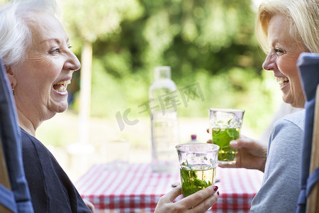 两个女人在花园里放松喝着冷饮笑着