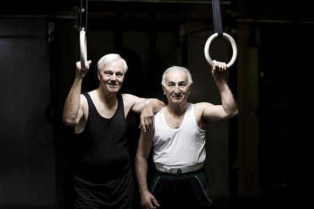 两名老年男子在黑暗的健身房里拿着健身戒指的肖像