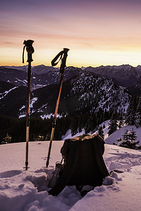 德国巴伐利亚州奥贝拉默高白雪覆盖的特菲尔斯塔特科普夫山顶上的登山杆和背包