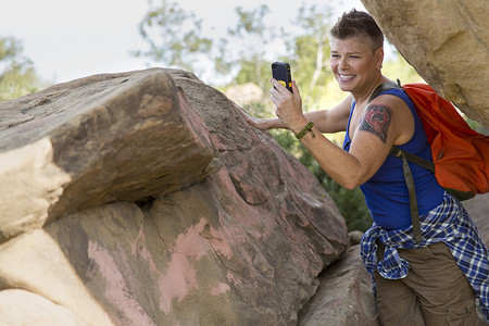 女徒步旅行者在岩石上使用智能手机进行自拍