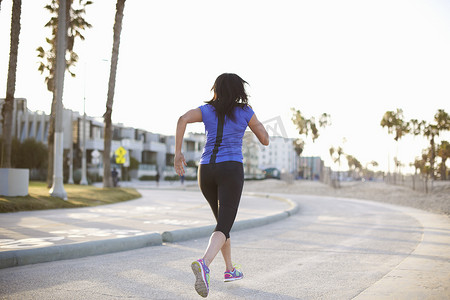 曲线大道摄影照片_身着运动服的女子在路上慢跑的全身后视