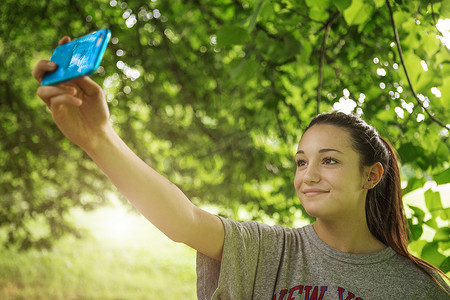 公园里十几岁的女孩在用智能手机自拍