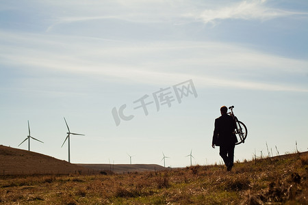 一名男子背着自行车上山前往风电场