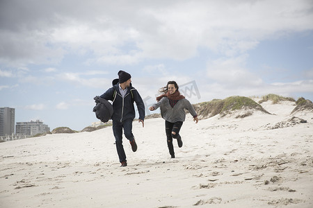 南非西开普省一对年轻夫妇在狂风肆虐的海滩上奔跑