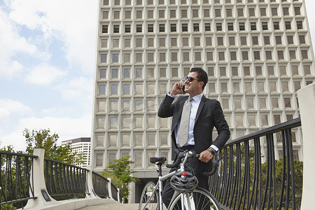 智能造摄影照片_中年商务人士手持自行车用智能手机打电话戴着太阳镜