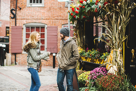 美国马萨诸塞州波士顿一对年轻夫妇在花店外的鹅卵石街道上聊天