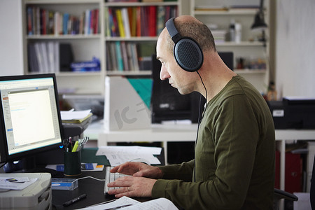 戴着耳机在创意工作室工作的成熟男人