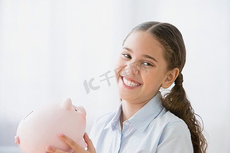 微笑的女孩拿着一个存钱罐