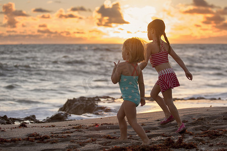女孩和姐姐在日出时在海滩上跑步美国佛罗里达州朱庇特岛吹石保护区