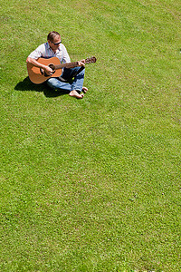 一名男子在草地上弹吉他