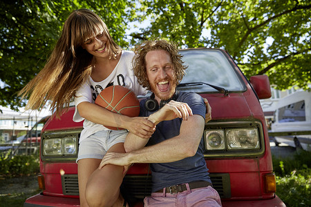 中年女性大笑摄影照片_年轻情侣在户外嬉戏大笑年轻女子拿着篮球