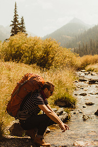 美国加利福尼亚州红杉国家公园矿泉王背着背包坐在小溪边的男子