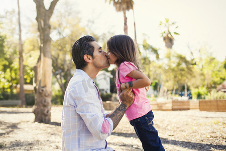 大家庭摄影照片_女孩在社区花园亲吻父亲