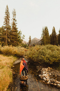 美国加利福尼亚州红杉国家公园矿泉王裹着睡袋在小溪钓鱼的男子