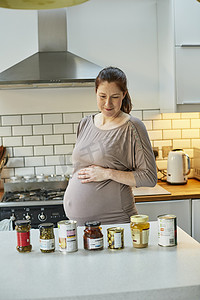 厨房里的孕妇看着厨房柜台上的罐头和罐头