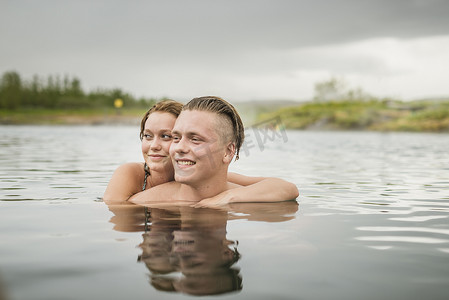 门德尔松摄影照片_冰岛福夫迪尔一对年轻夫妇在秘密泻湖温泉边看边