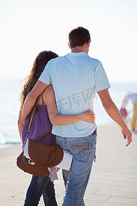爱情发生摄影照片_一对情侣在海滩上散步和拥抱