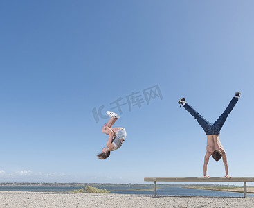 女孩翻筋斗男孩在沙滩板凳上倒立